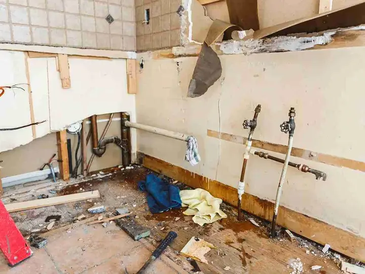 Opened wall and wet floor behind failed supply valves in a Sandy, UT kitchen